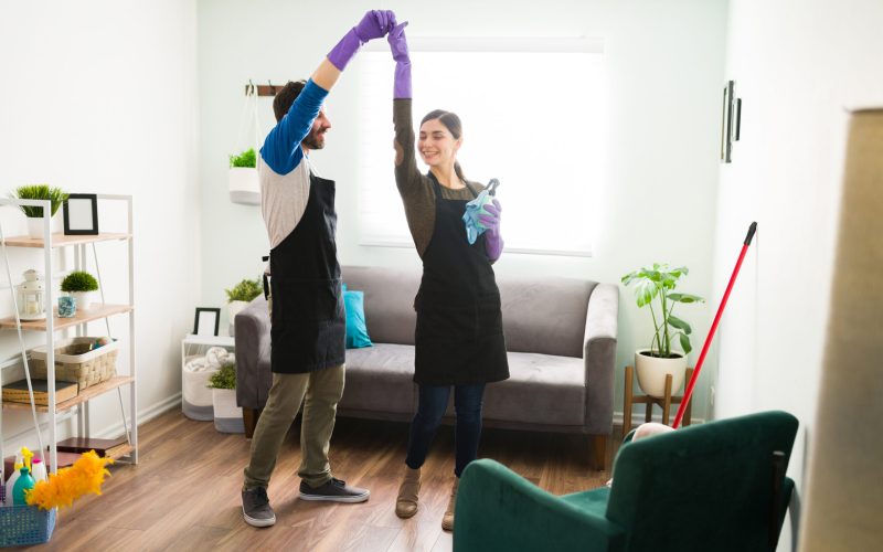 Full length view of an attractive Latin couple dancing and having fun while doing all the house work at home